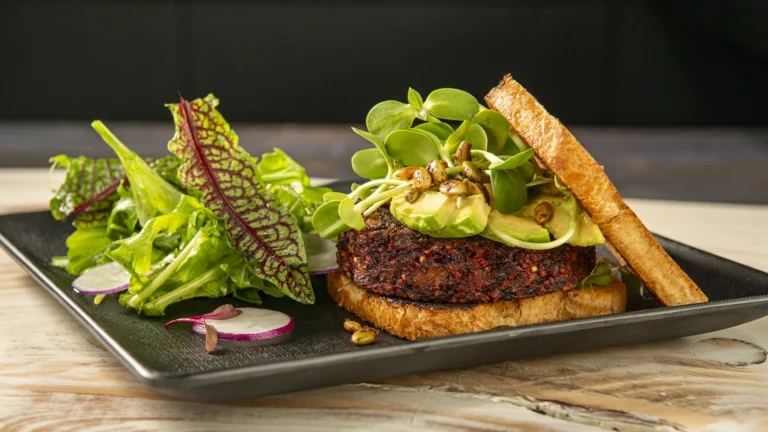 veggie burger with salad avocado nuts sprouts wood surface by slade photo
